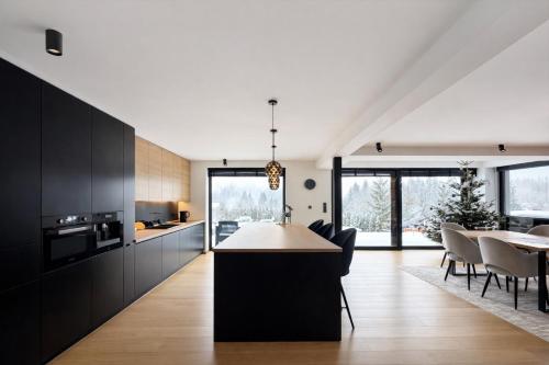 een keuken en eetkamer met zwarte kasten en een tafel bij Willa Black Wood in Istebna
