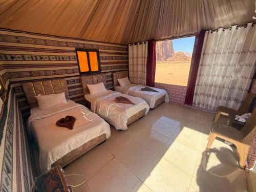 two beds in a room with a view of the desert at Starry Nights Luxury Camp in Wadi Rum