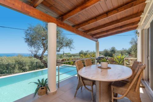 a patio with a table and chairs and a swimming pool at Villa Gisele with Private Pool in Tragaki