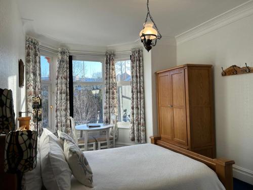 a bedroom with a bed and a window and a table at Greylands Guest House in Llandrindod Wells