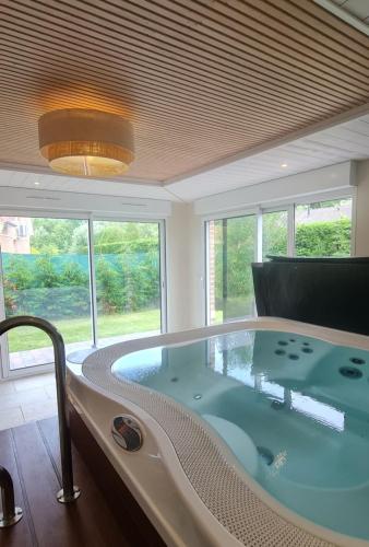 a bath tub in a room with a large window at Merlimont Spa Gîte Au Gîte des Colibris Merlimont in Merlimont