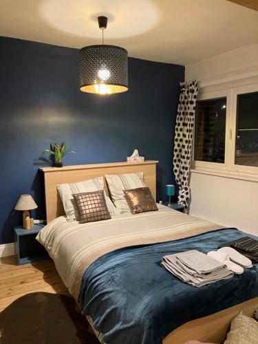 una camera da letto con un letto grande con una parete blu di Maison Corneille proche de Lille a Hem