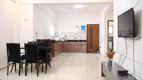 a dining room with a table and black chairs at Blossom Service Apartment in Mysore