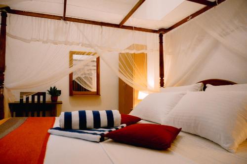 a bedroom with a white bed with red and white pillows at Brown Birds Villa in Tangalle