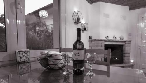 a bottle of wine and two glasses on a table at Gurba's House in Aridaia