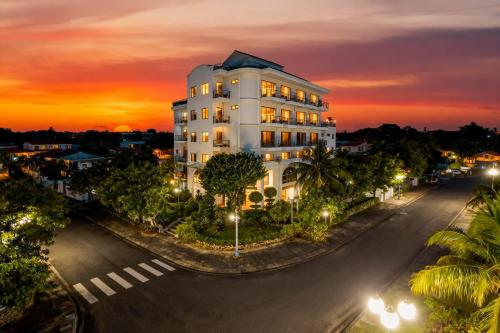 un edificio bianco su una strada con un tramonto di JM Hoi An Beach Hotel - Free Shuttle Car To Old Town a Hoi An
