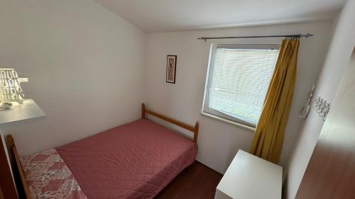 a small bedroom with a red bed and a window at Apartman a tengernél in Vir