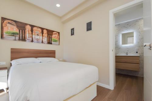 a white bedroom with a large bed and a window at San Ambrosio in Granada