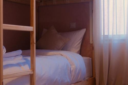 un letto a castello con lenzuola e cuscini bianchi in una camera di Catamaran Surf House a Agadir nʼ Aït Sa