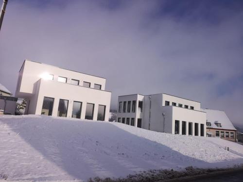 een berg sneeuw voor twee gebouwen bij eifel24, neu, modern mit Dachterrasse in Schwirzheim