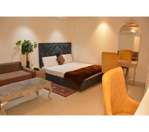 a bedroom with a bed and a couch and a table at The Kuber Hotel in Bareilly