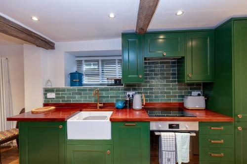 a green kitchen with green cabinets and a sink at A Hidden Gem in the Heart of Wells, Somerset in Wells