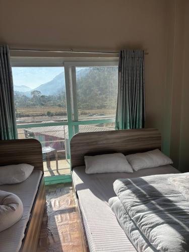 two beds in a room with a large window at Gauthali Inn in Netadurling