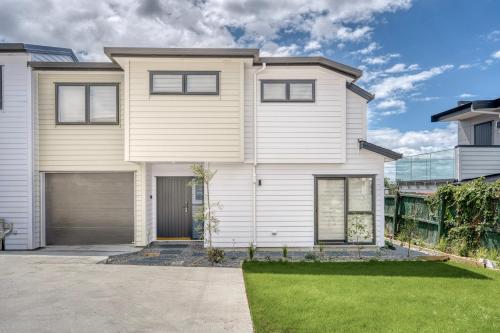 a large white house with a garage at Cosy & Contemporary entire 3 Bedroom Airport Retreat in Auckland