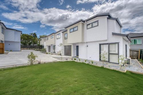 a row of white houses with a yard at Cosy & Contemporary entire 3 Bedroom Airport Retreat in Auckland