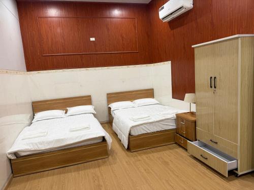 two beds in a room with wood paneled walls at Motel Anh Khoa in Tam Kỳ