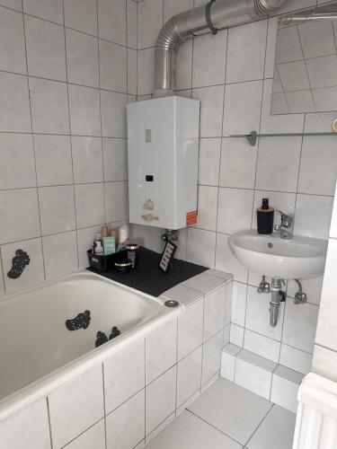 a white bathroom with a tub and a sink at Gemütliche Wohnung über den Dächern von Gevelsberg in Gevelsberg