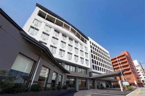 a white building on a street in a city at Hotel New Tsuruta in Beppu