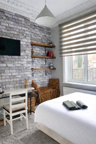 a bedroom with a bed and a desk and a brick wall at CityStay London in London