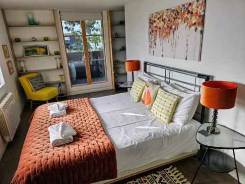 a bedroom with a bed and a chair and a window at Regatta - A lakeview apartment in Thorpeness - Aldeburgh Coastal Cottages in Thorpeness