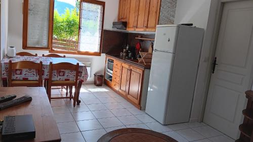 a kitchen with a white refrigerator next to a table at Rez de Jardin Guillestre in Guillestre