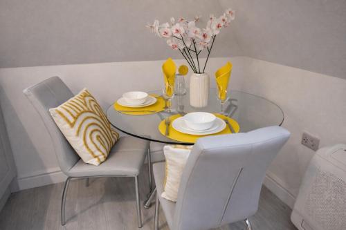 a dining room table with chairs and a vase with flowers at Beautiful cosy attic studio flat king size bed in central Beeston in Nottingham in Beeston