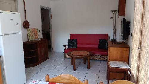 a living room with a red couch and a table at Rez de Jardin Guillestre in Guillestre