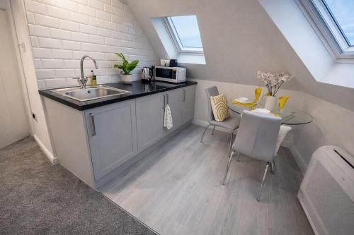 a small kitchen with a sink and a table at Beautiful cosy attic studio flat king size bed in central Beeston in Nottingham in Beeston