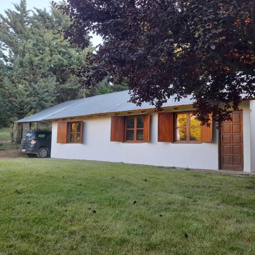 a white house with a garage and a yard at Cabaña Del Viento in Huinganco