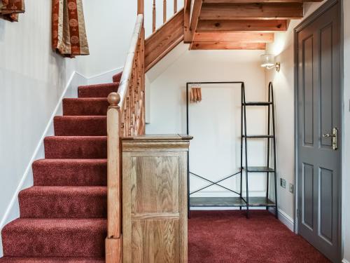 a staircase in a house with red carpet and a wooden door at Fairhead Cottage in Grosmont