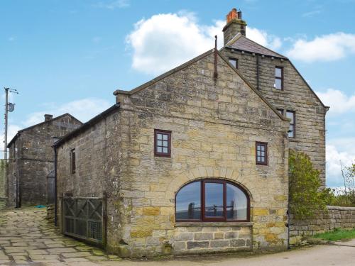an old stone building with a large window at Fairhead Cottage in Grosmont