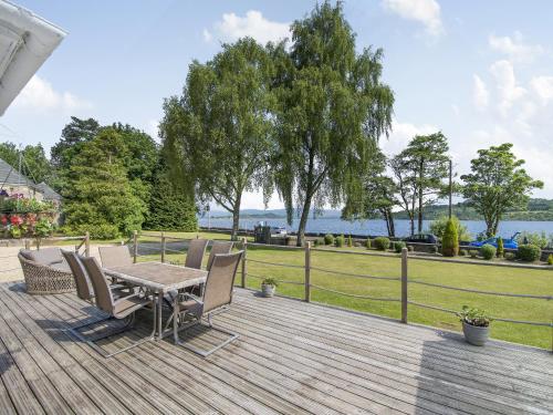 een houten terras met een tafel en stoelen erop bij Duck Bay Cottage 2 - Uk43935 in Balloch