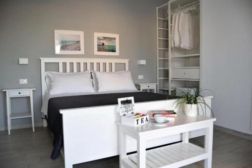 ein Schlafzimmer mit einem weißen Bett und einem weißen Tisch in der Unterkunft Arneo Terra del Sole B&B in Torre Lapillo