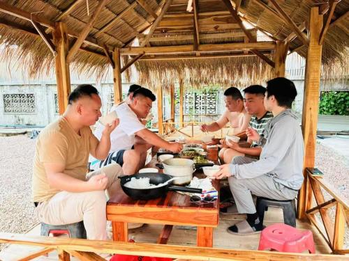 un gruppo di uomini seduti attorno a un tavolo che mangiano cibo di JD Hotel a Vientiane