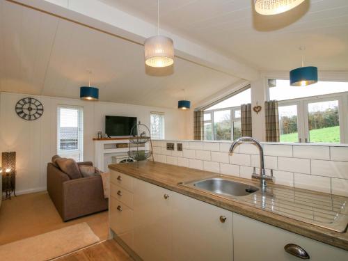 a kitchen with a sink and a living room at The Hedgerows - Hillview Lodges in Kidderminster