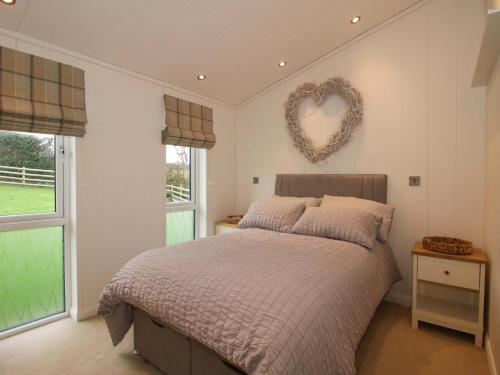 a bedroom with a bed with a heart sign on the wall at The Hedgerows - Hillview Lodges in Kidderminster