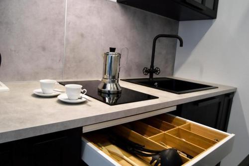 eine Küchentheke mit Spüle und zwei Tassen in der Unterkunft Arneo Terra del Sole B&B in Torre Lapillo