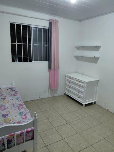 a bedroom with a bed and a dresser and a window at Casa Praça in Paripueira