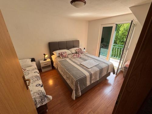 a bedroom with a bed and a balcony at Apartmani Kežić Drvenik in Drvenik