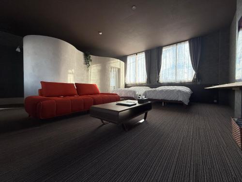 a living room with a red couch and a bed at 欒裏町ouchi uramachi in Matsumoto