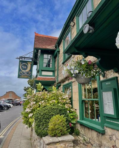 a building with green windows and flowers on a street at The Bugle Coaching Inn in Yarmouth