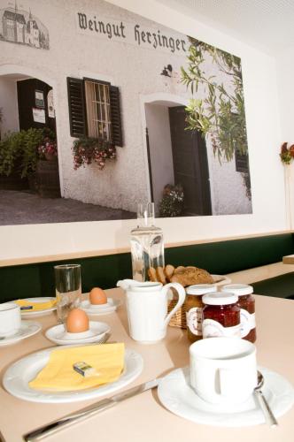 a table with plates and cups on it with food at Weingut Herzinger in Franzhausen