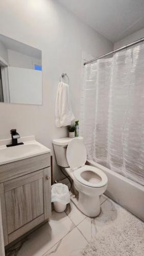 a white bathroom with a toilet and a sink at Private rooms in a shared two bedrooms apartment in Montréal