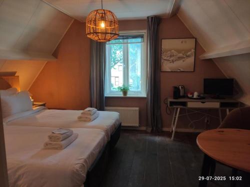 een hotelkamer met twee bedden en een raam bij 't Wapen van Middelie in Middelie