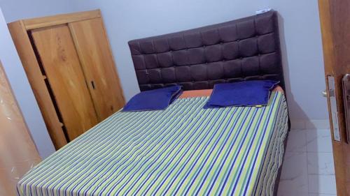 a bed with two blue pillows on top of it at Apparemment 2 chambres- Lemba Salongo in Kinshasa
