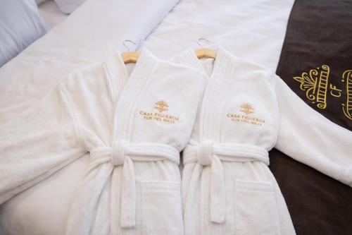 two white robes sitting on top of a bed at Casa Figueroa - Boutique Hotel- Adults Only in Cairo