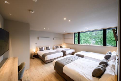 a bedroom with two beds and a large window at Villa Cielo Hakone Luxury - Mt Fuji View Private Onsen & Sauna シエロ箱根仙石原 in Hakone