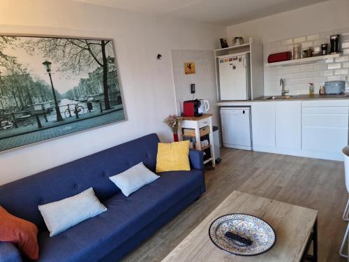 a living room with a blue couch and a kitchen at Johan's B&B - Since 2014 roofterrace and cheap parking in Amsterdam