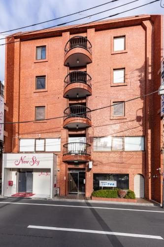 a red brick building with balconies on a street at Tourist Hotel New Aoki 観光ホテル ニュー青木 in Tokyo