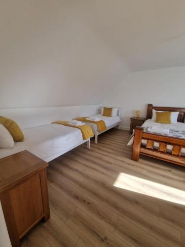 two beds in a room with wooden floors at The Lake House, cong in Cong